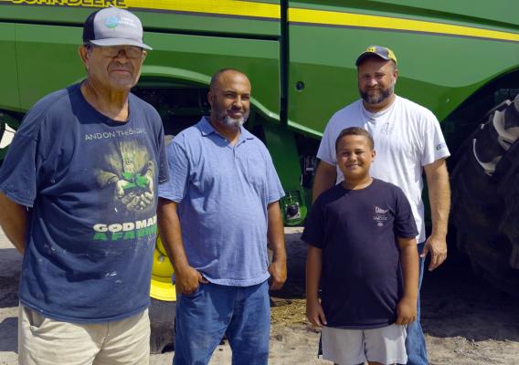 Four people standing in front of a tractor